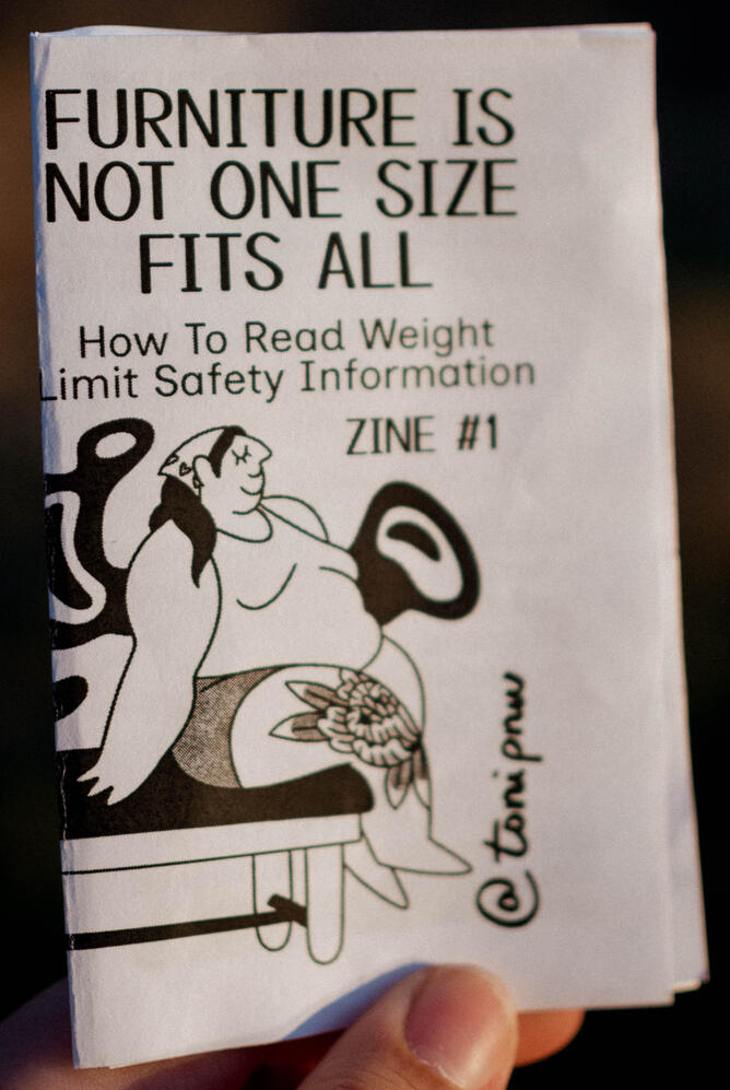 Untitled A photo of a zine cover depicting a fat person sitting on a flat tattoo bed. This zine is titled "Furniture Is Not One Size Fits All"