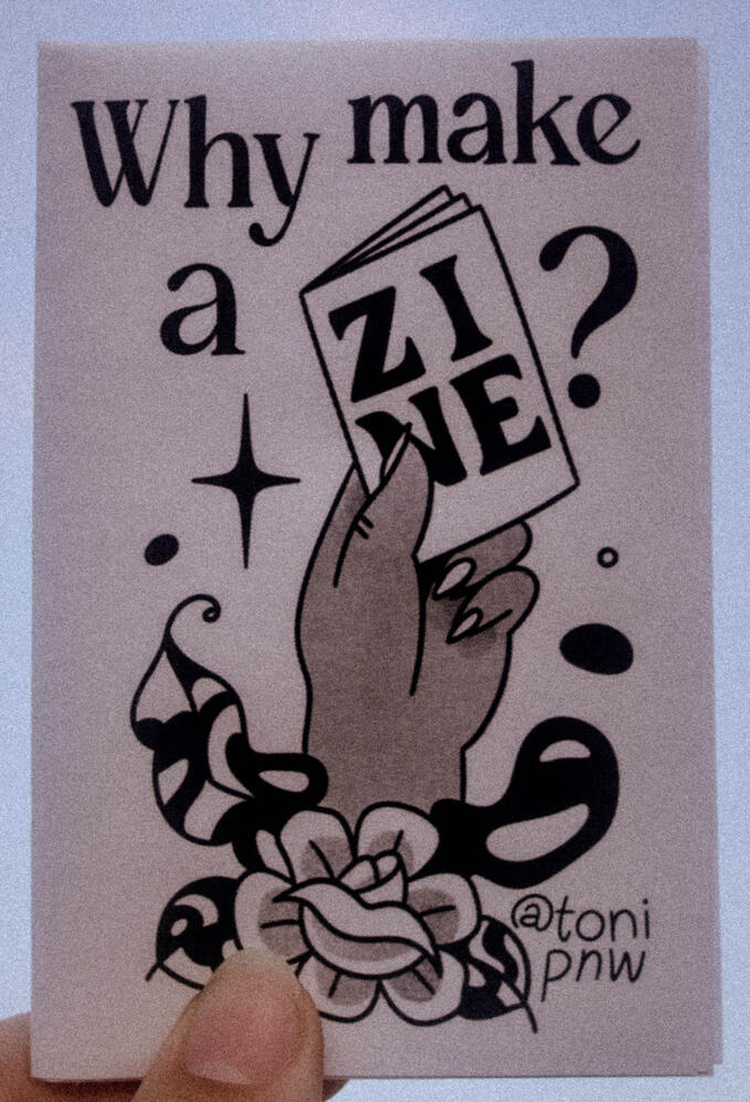 Untitled A photo of a zine cover depicting a hand holding a zine. This zine is titled "Why Make A Zine?"